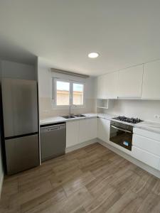 una cocina con armarios blancos y electrodomésticos de acero inoxidable en Apartamento Playa Oliva Deluxe en Oliva