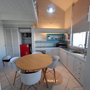 eine Küche mit einem Holztisch und weißen Stühlen in der Unterkunft Resort Loft & Spa Villa #8 in Mandurah