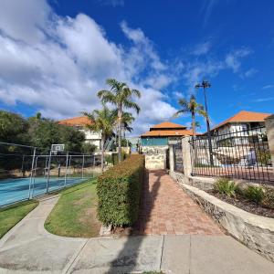 einen Gang neben einem Pool mit Palmen und einem Zaun in der Unterkunft Resort Loft & Spa Villa #8 in Mandurah