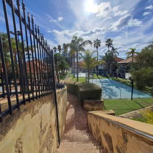 a fence next to a swimming pool with palm trees at Resort Loft & Spa Villa #8 in Mandurah