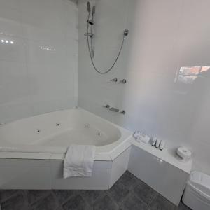 a white bathroom with a tub and a toilet at Resort Loft & Spa Villa #8 in Mandurah +5 photos
