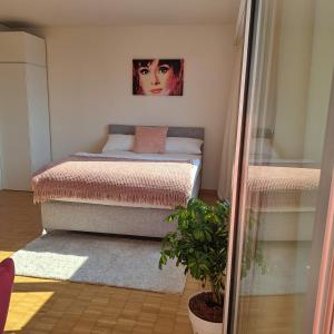 クロイツリンゲンにあるSonniges 1-Zimmerappartement mit Blick über Kreuzlingenのベッドルーム1室(ベッド2台付)が備わります。壁には絵画が飾られています。