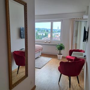 クロイツリンゲンにあるSonniges 1-Zimmerappartement mit Blick über Kreuzlingenのリビングルーム(鏡、赤い椅子、テーブル付)