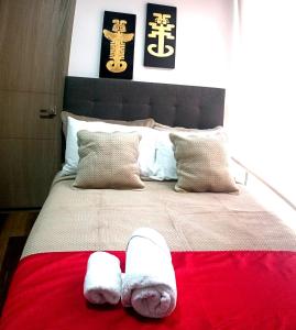 ein Bett mit zwei weißen Handtüchern auf einer roten Decke in der Unterkunft Beautiful Loft 35 Movistar Arena - Campin - Chapinero Bogota Colombia HOSTMI in Bogotá