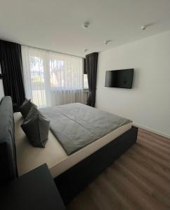 a bedroom with a large bed and a flat screen tv at EZì Apartment in Šiauliai