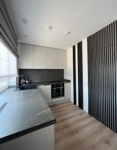 a kitchen with white cabinets and a black counter top at EZì Apartment in Šiauliai
