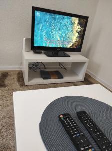 a television and two remote controls on a white stand at Apartment Kraljevac in Visoko