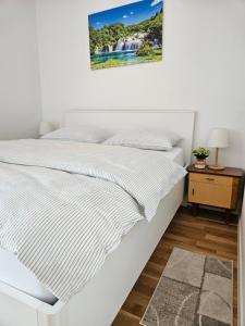 a white bed in a bedroom with a picture on the wall at Old Town Đurđevac- 1 garažno mjesto, besplatan wifi te ulaznice za Hrvatsku saharu, mini zoo in Ðurđevac