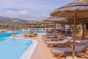 un grupo de sillas y sombrillas junto a una piscina en Hotel Airone, en Baja Sardinia