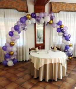Rocchetta LigureHotel Da Bruno的桌旁的气球拱,带有紫色和金色气球