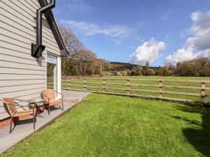 um alpendre com duas cadeiras e uma mesa ao lado de uma cerca em Cornelyn Bach em St Asaph