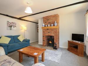 a living room with a blue couch and a fireplace at Hadleigh Farm Cottage in King's Lynn