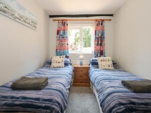 2 Einzelbetten in einem Zimmer mit Fenster in der Unterkunft Hadleigh Farm Cottage in Kings Lynn