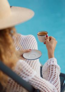 Una donna seduta su una sedia con una tazza di caffè di Aria di Mare Apartments a Tivat