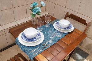 a table with plates and glasses and a vase with flowers at Casa de 2 Suítes com Internet Rápida e Comodidades in Belo Horizonte