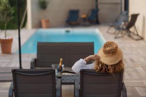 une femme assise sur une chaise en face d'une piscine dans l'établissement Aria di Mare Apartments, à Tivat