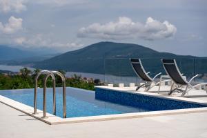 a pool with chairs and a view of the mountains at Villa Trebesin in Herceg-Novi