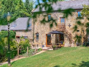 a stone house with a table and an umbrella at Lakeview Cottage - Uk44099 in Carsington