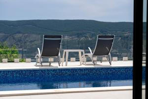 dwa krzesła i stół obok basenu w obiekcie Villa Trebesin w mieście Herceg Novi