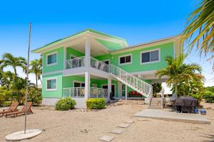 a green house with palm trees in front of it at Shady Deck in Key Colony Beach
