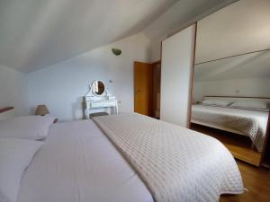 a white bedroom with two beds and a mirror at Dalmatian Villa Denis in Bol