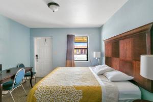 a bedroom with a bed and a desk and a table and chair at Deluxe Inn in Dania Beach