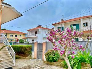 a house with a fence and a tree with purple flowers at Cascais Garden Villa in Cascais