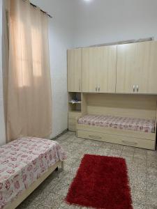 Schlafzimmer mit einem Bett, Schränken und einem roten Teppich in der Unterkunft La Casa di Giusy in Lampedusa