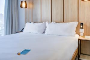 a bed with white sheets and pillows in a hotel room at Radisson Pinheiros in São Paulo