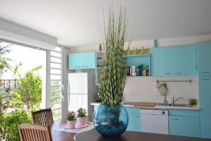 una cocina con una mesa con un gran jarrón azul con una planta en Unique : Pieds dans l'eau face au lagon, en Sainte-Anne