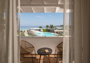 a balcony with a view of a pool and the ocean at Antigoni Seaside Resort in Ormos Panagias