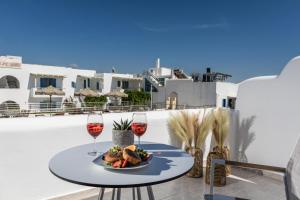 une table avec une assiette de nourriture et deux verres de vin dans l'établissement Naxos Leisure, à Ágios Prokópios