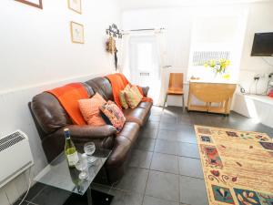 a living room with a brown leather couch and a table at Bridge Cottage in Haltwhistle