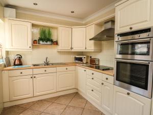 a white kitchen with white cabinets and appliances at Bari in Aberaeron