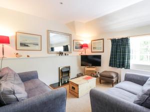 a living room with two couches and a tv at The Mews Flat in Dalswinton