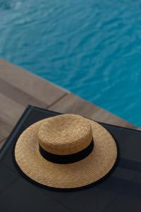 Aria di Mare Apartments في تيفات: وجود قبعة من القش بجانب حمام السباحة