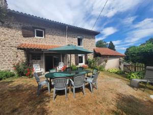 a patio with a table with chairs and an umbrella at Les Ronzières in Les Salles