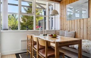 a dining room with a table and chairs and windows at Amazing Home In Væggerløse With Kitchen in Marielyst