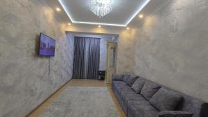 a living room with a couch and a television on a wall at Красивая квартира в центре города. in Dushanbe