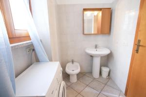 een badkamer met een wastafel, een toilet en een spiegel bij Villetta La Terrazza in Chiessi