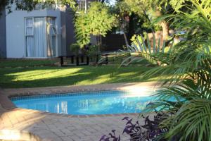 a swimming pool in a yard with trees and a house at Ecolux Boutique Hotel in Komatipoort