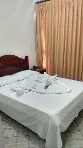 a bed with two white dishes on top of it at HOTEL LÉO in Piranguinho