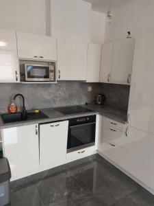 cocina blanca con armarios blancos y microondas en Bezbariérový apartmán Lodenica - v tesnej blízkosti Adelli centra, en Piešťany