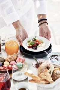 a chef holding a plate of food on a table at Antigoni Seaside Resort in Ormos Panagias
