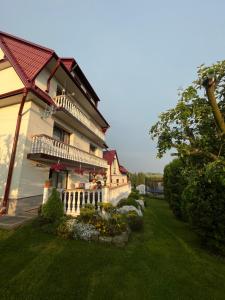 a large house with a porch and a grass yard at Agroturystyka u Ireny in Mizerna