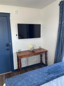 a bedroom with a table with a tv on the wall at Duncklee Room 202, Hyland Hotel in Palmer