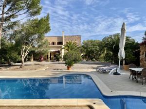 uma piscina com uma mesa e um guarda-sol em Finca S'olivar d'es Coscois em Santa Margalida