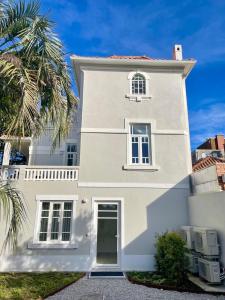 una casa blanca con una palmera delante de ella en Uporto House Palace en Oporto