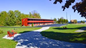 un edificio rojo con un banco rojo en un parque en Cedar Hill Lodge, en Saint Ignace