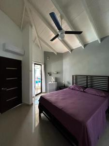 um quarto com uma cama roxa e uma ventoinha de tecto em Casa MIA em Cabarete